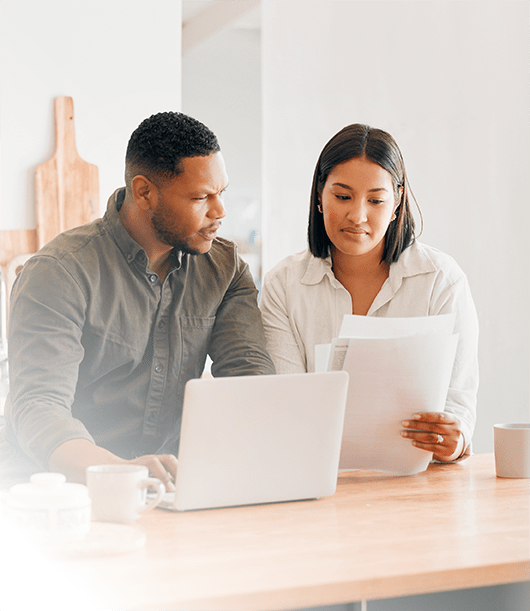 Couple reviewing documents with laptop on table