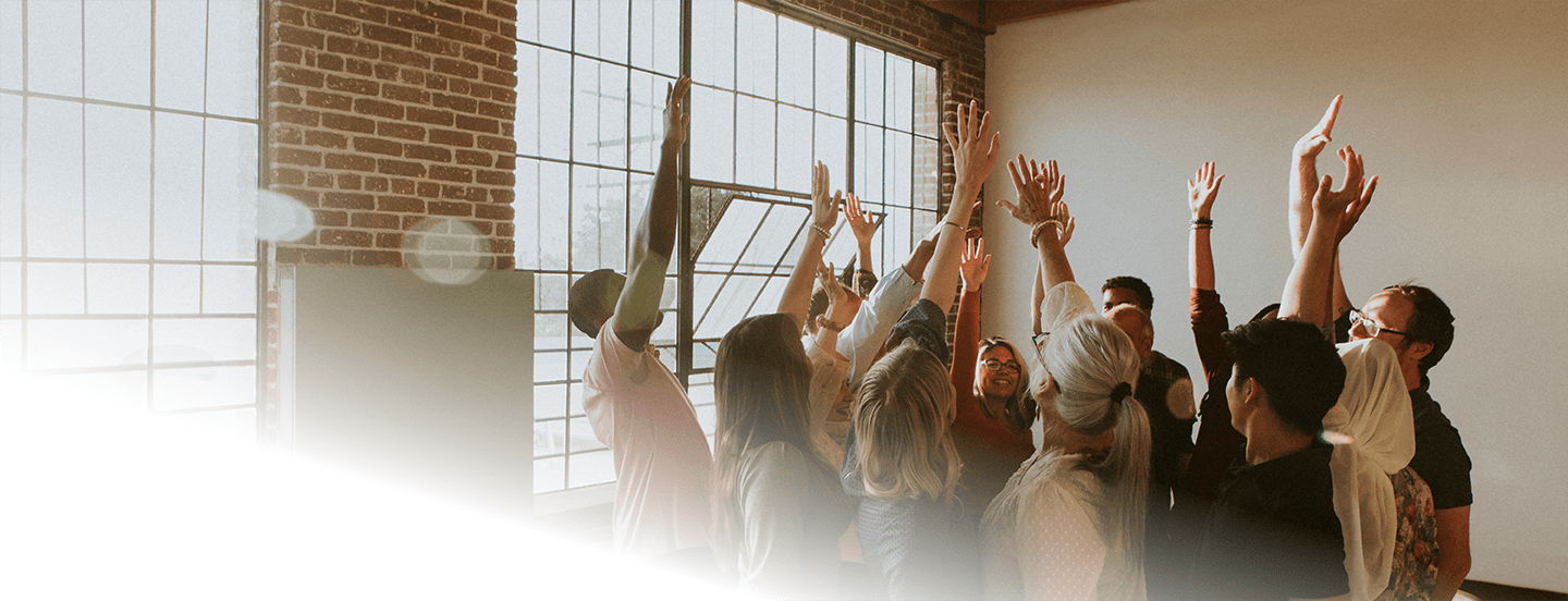 Group cheering with raised hands in sunlit loft